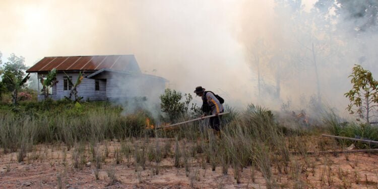 Ilustrasi anggota polisi memadamkan api pada lahan kering yang terbakar di Kota Dumai Riau Foto Utusan Rakyat