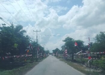 Suasana semarak di salah satu ruas jalan di Kecamatan Bunga Raya, Siak, yang dihiasi dengan bendera Merah Putih dan umbul-umbul untuk menyambut HUT Kemerdekaan RI ke-80.