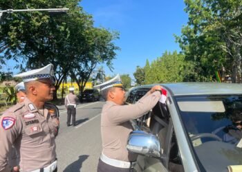 Personel Satlantas Polres Kampar memasangkan bendera Merah Putih di kendaraan warga dalam kegiatan "Gerakan Polantas Menyapa" untuk menyemarakkan HUT Kemerdekaan RI ke-80 di Jalan Prof. M. Yamin, Bangkinang Kota.