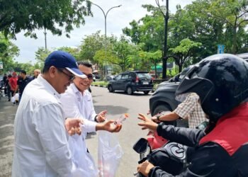 Ketua PWI Riau, Raja Isyam Azwar (berkacamata, kemeja putih), bersama pengurus PWI Riau membagikan paket nasi dan minuman kepada pengendara dalam kegiatan Jumat Berkah di depan Kantor PWI Riau, Jalan Arifin Achmad, Pekanbaru, Jumat (12/9/2025).